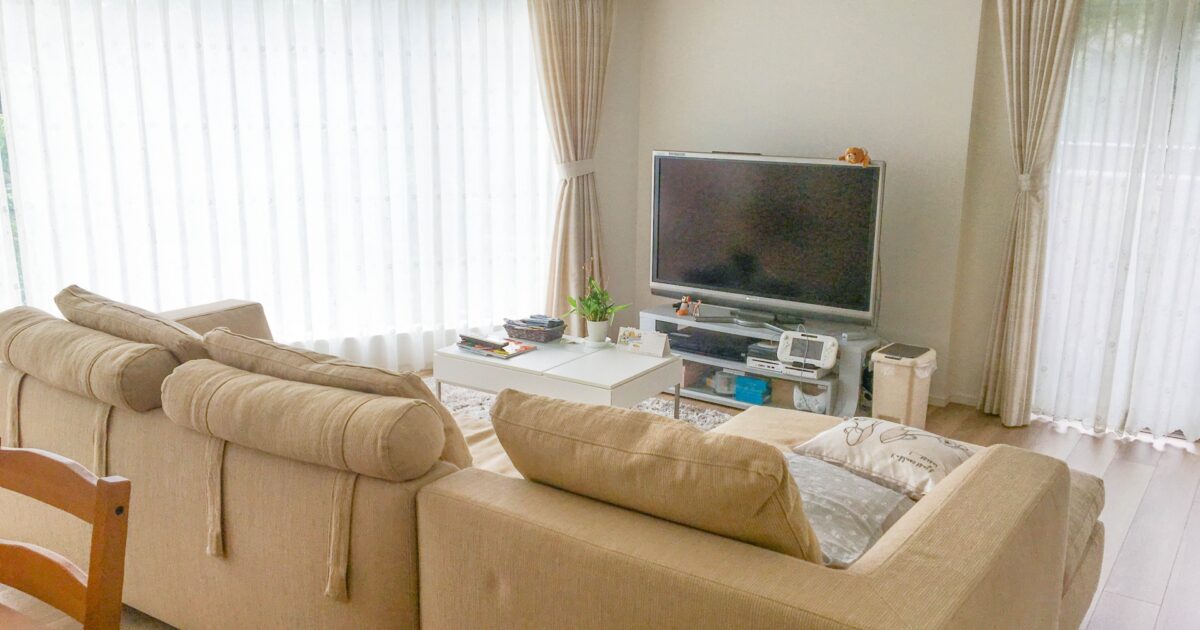 大型テレビとベージュソファがあるナチュラルなリビングルーム